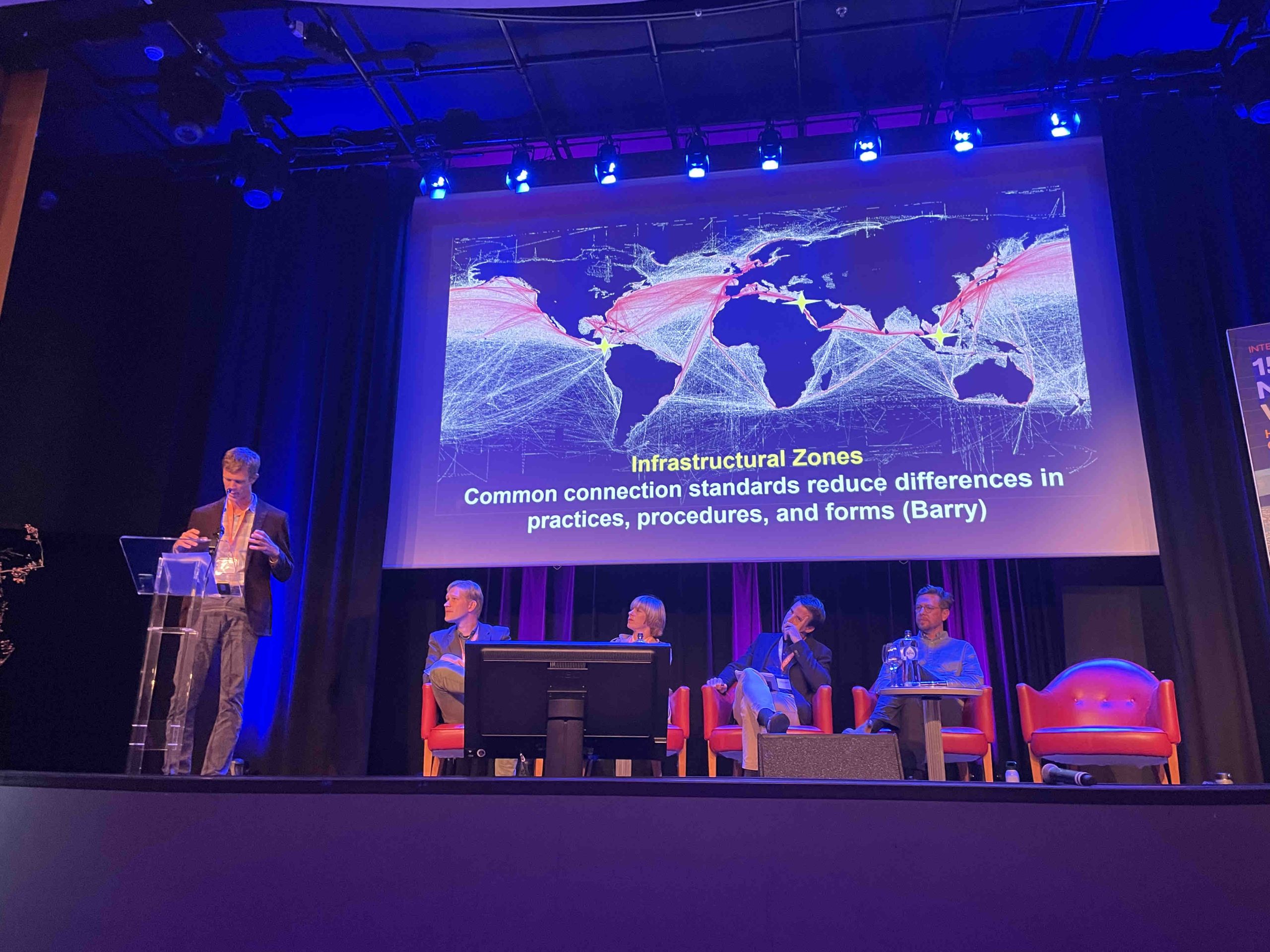 Ashley Carse (standing to the left) presenting at The International Symposium: The 150 Year New Waterway, Rotterdam, Oct 13, 2022. Joshua Lewis sitting (right). Photo by Henrik Ernstson, 2022.